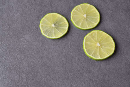 Cut into slices of lime on a dark black background, empty space for your text