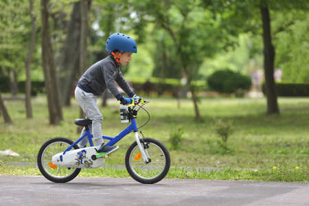 Happy kid boy of 5 years having fun in outdoor park with a bicycle on beautiful spring day. Active child making sports. Safety sports leisure with kids conceptの写真素材