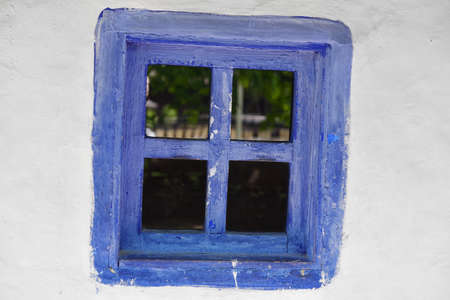Closed vintage blue window on white wall of old house in romaniaの写真素材