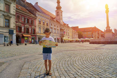 Young boy tourist with city map stay on the old european streetの写真素材