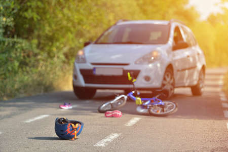 Close-up of a bicycling helmet fallen on the asphalt next to a bicycle after car accident on the street in the cityの写真素材