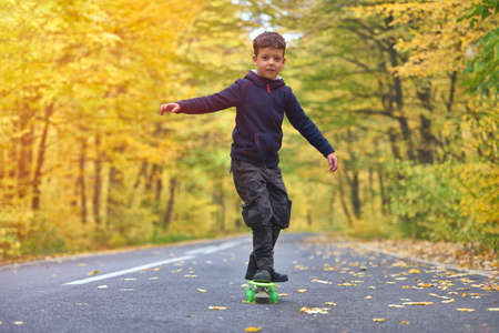 Kid skateboarder doing skateboard tricks in autumn environmentの写真素材