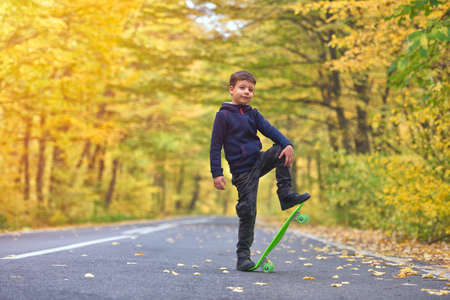 Kid skateboarder doing skateboard tricks in autumn environmentの写真素材