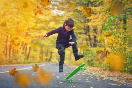 Kid skateboarder doing skateboard tricks in autumn environmentの写真素材