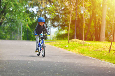 Happy kid boy of 5 years having fun in outdoor park with a bicycle on beautiful spring day. Active child making sports. Safety sports leisure with kids conceptの写真素材