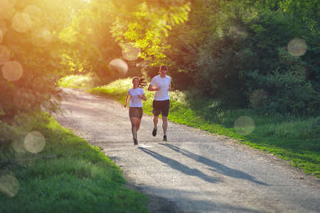 Young people jogging and exercising in nature, in morning sunrise warm lightの写真素材