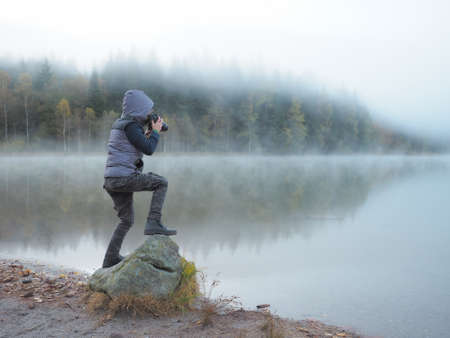 Creative child, kid photographer (a little boy) with a camera taking landscape pictures near la lakeの写真素材
