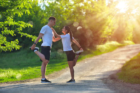 Young couple stretching legs on a road at the parkの写真素材