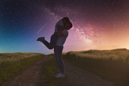 Silhouettes of a young couple in love under the starry sky with milky way.の写真素材