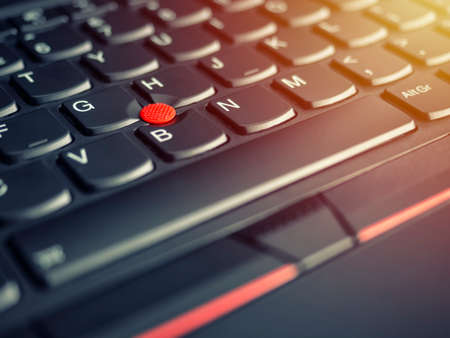 A close-up photo of the red pointing stick of on a laptop keyboard