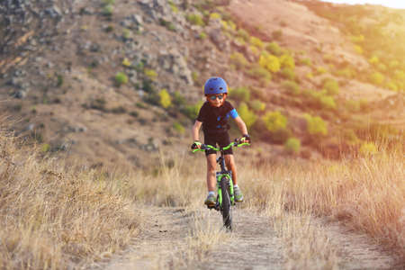 Happy kid boy of 7 years having fun in autumn park with a bicycle on beautiful fall day. Active child wearing bike helmetの写真素材