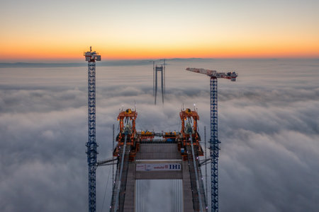 Braila, Romania - November 13, 2022: IHI Webuild japonese company building the bridge over Danube River near Braila City in Romania. Panoramic aerial drone view from above of the suspended bridge.のeditorial素材
