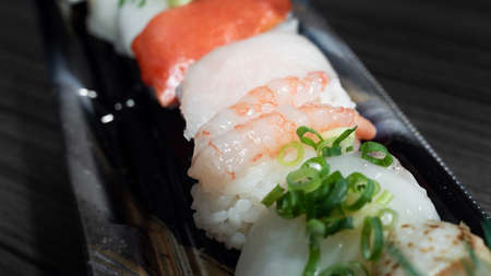 Closeupâ piecesâ ofâ sushiâ withâ a variety ofâ rawâ meat toppingsâ onâ a plasticâ container.の写真素材