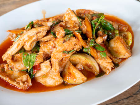 Thaiâ hot andâ spicy stir-friedâ fish withâ local ingredients; redâ chilliâ paste, â pepercorn, basilâ leaf, andâ eggplant, onâ whiteâ plate.の写真素材