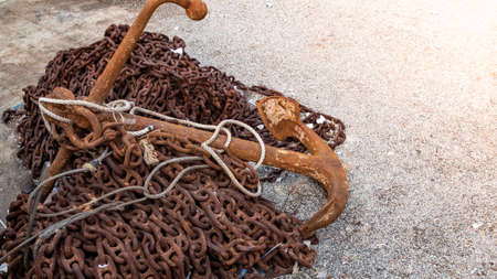 Abandoned rusty anchor left on pile of rusty metal chain and rubbish.の写真素材