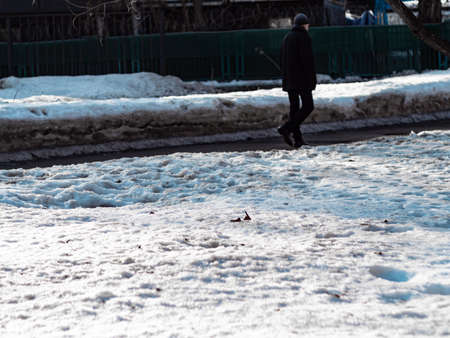 Field covered with thick snow with blurred background of walking man in dirted passage.の写真素材