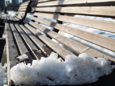Closeupâ shotâ ofâ leftâoverâ snow onâ woodenâ bench.の写真素材