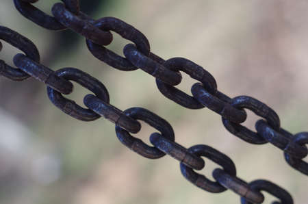 Two tense rusrty chains closeup