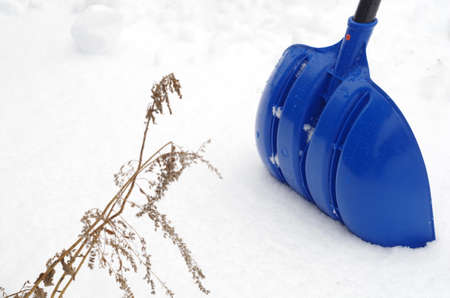 The blue plastic snow shovel stuck in the snowの写真素材