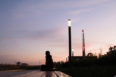 lady on a bench in silhouette admiring the sunsetの写真素材