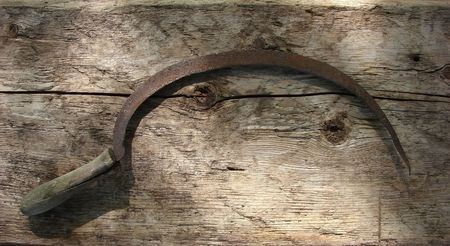 vintage rusty sickle on an old plateの写真素材