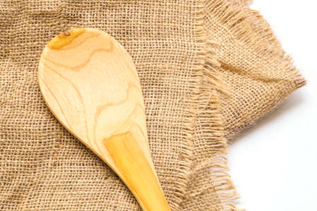 Empty wooden spoon on burlap background for food products, food ingredients display. Clean food, organic food, natural food concept. Food and kitchen background.の写真素材