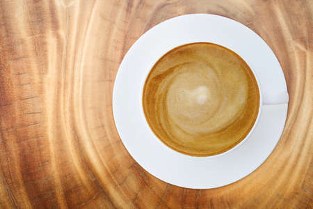 Top view of hot coffee cappuccino latte cup with saucer on wood texture abstract background.の写真素材