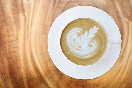 Top view of hot coffee cappuccino latte cup with saucer on wood texture abstract background.の写真素材