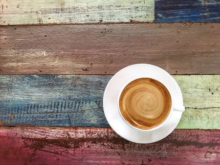 Top view of hot coffee cappuccino cup with spiral milk foam on painted wooden planks table background.の写真素材