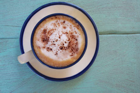 Top view of hot coffee  cappuccino cup or hot drink cocoa with milk foam and cinnamon powder on light blue pastel painted wood table background.の写真素材