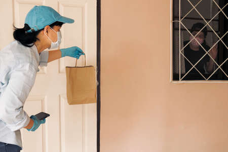 Safe contactless delivery to home during Coronavirus COVID-19 pandemic. Food delivery worker courier...