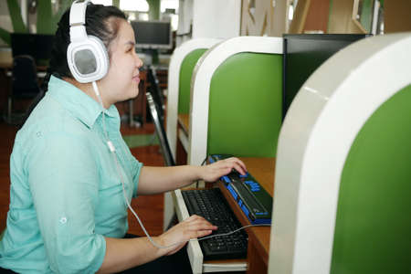 Asian woman with blindness disability using computer with refreshable braille display or braille...