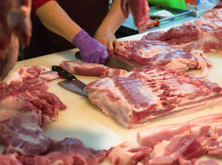 Wufeng, Taichung, Taiwan - April 12, 2020: A pork stall owner cuts and sells fresh pork raw meat in Wufeng traditional market at Wufeng, Taichung, Taiwan during pandemicのeditorial素材