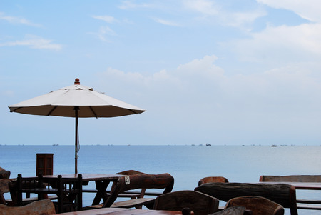 Dining table and umbrella of restaurant by the sea with sea and sky background.の写真素材