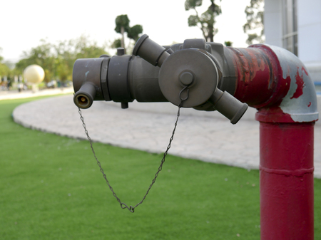 Close-up red fire hydrant spigot for connecting the fire hose in the lawn.