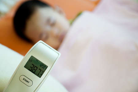 Close-up of the thermometer after measuring the temperature of a child with a fever, Climate change makes the children sick.の写真素材