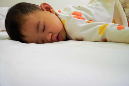 The little boy was sleeping on the bed, sleeping in the prone position.の写真素材