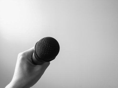Close-up microphone in left hand of singer at concert with copy space, Singing concept, Black and white.の写真素材