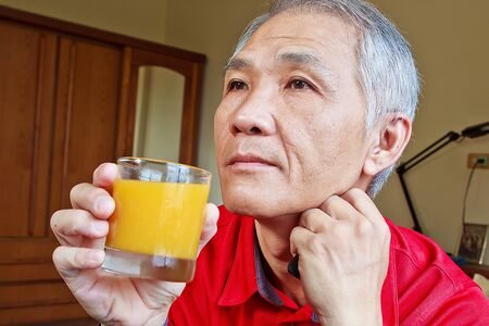 A Chinese middle-aged Man who drinking Orange juiceの写真素材