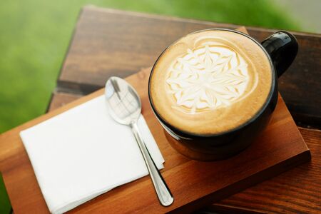 hot cappuccino coffee with white note Served on wooden tray in lawn background