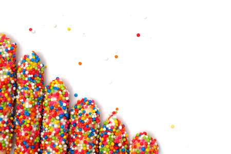 Colorful biscuit stick coated enamel rainbow sugar with white space background for writing wordingの写真素材