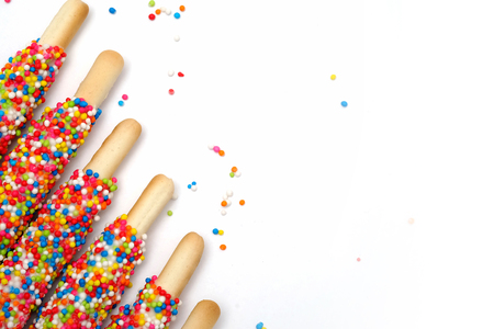 Colorful biscuit stick coated enamel rainbow sugar with white space background for writing wordingの写真素材