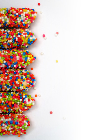 Colorful biscuit stick coated enamel rainbow sugar with white space background for writing wordingの写真素材