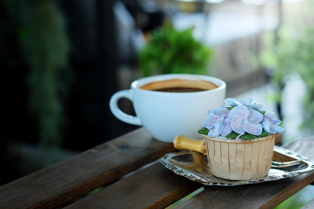 Blue cupcake design cream like blue Hydrangea flower Served with hot black coffee on wooden table background and have some space for write wordingの写真素材