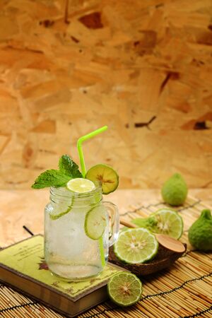Kaffir lime So, Bergamot soda Cool drink, Thailand tradition Herb for Treatment of Acid Reflux, with Oriental Earth tone map background.Have some space for write wordingの写真素材