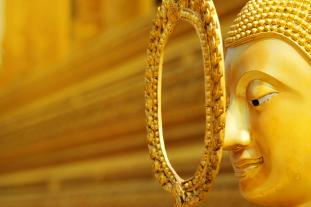 golden calm face of Buddha statue with golden background. Have some space for text or wording about Principlesの写真素材