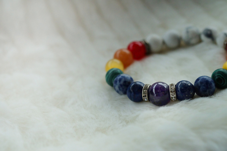 mineral Chakra color luck fortune stone bracelet on white wool background.  Amulet accessories for good good lucky fortune and happy lifeの写真素材