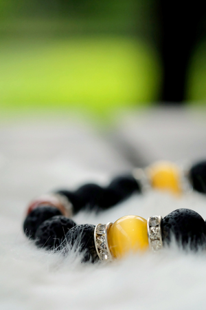 yellow Chrysoberyl Cat's Eye stone and Lava stone.Luck fortune stone bracelet  with yellow and black tone on white wool background  . Amulet accessories for good good lucky fortune and happy lifeの写真素材