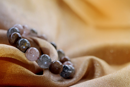 luxurious variegated mineral Rutile Quartz or  Venus hair stone bracelet on golden fabric background. Amulet accessories for good good lucky fortune and happy lifeの写真素材