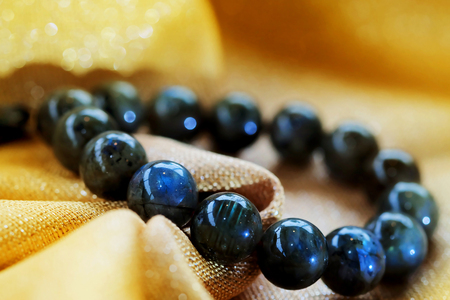 Labradorite lucky stone on golden fabric background. Amulet accessories for good lucky fortune and happy lifeの写真素材